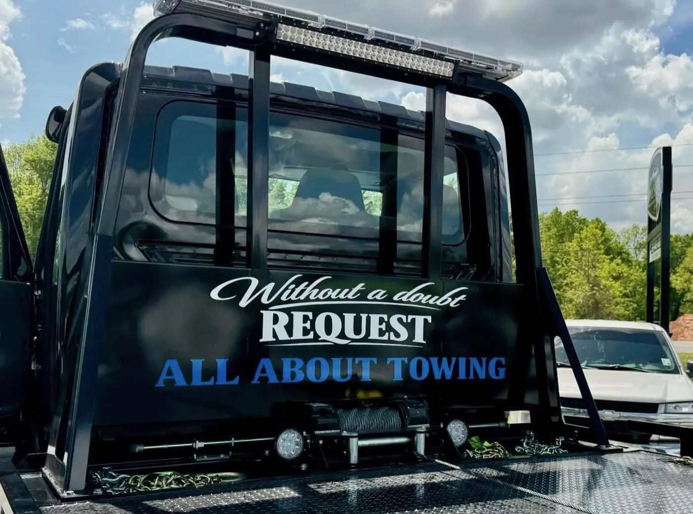 Rear of an All About Towing flatbed truck with company branding in Alexandria, LA
